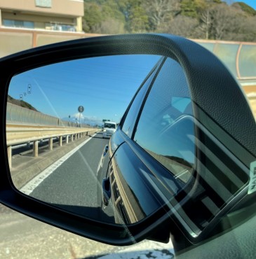 高速道路走行中の寺所有の自動車のミラーです 遠く道路標識の向こうに富士山が見えます