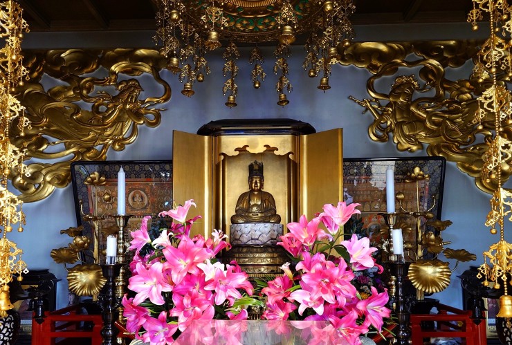 白王山中台院福性寺のご本尊様胎蔵界大日如来様 蓮華座の修理は終わっていません 生花は檀家様の奉納 正面の如来様の厨子の左右は曼荼羅 情報の壁の左右は飛天