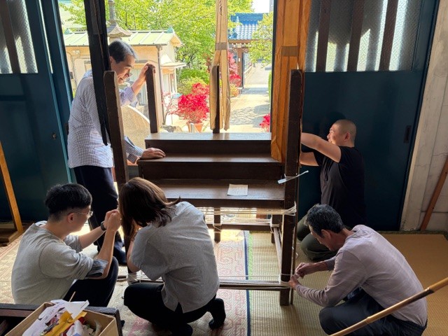 施餓鬼壇を組み立てています あいかわらず住職は手を添えるだけでサボっています 外のツツジが美しいです 会計係が撮影